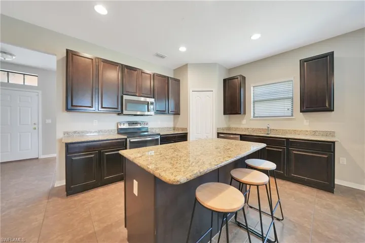 Kitchen featuring a kitchen breakfast bar, a kitchen island, visible vents, dark brown cabinetry, and appliances with stainless steel finishes