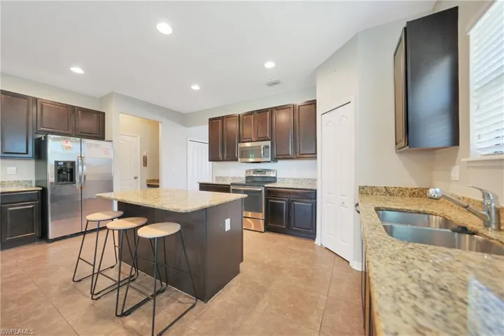 Kitchen featuring a sink, a breakfast bar area, appliances with stainless steel finishes, a center island, and visible vents