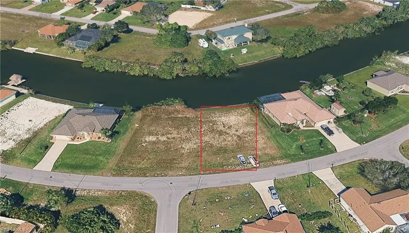 Aerial perspective of suburban area with a nearby body of water and property boundaries highlighted