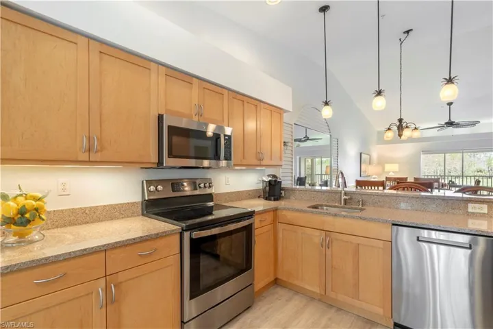 Kitchen featuring appliances with stainless steel finishes, decorative light fixtures, ceiling fan, and sink