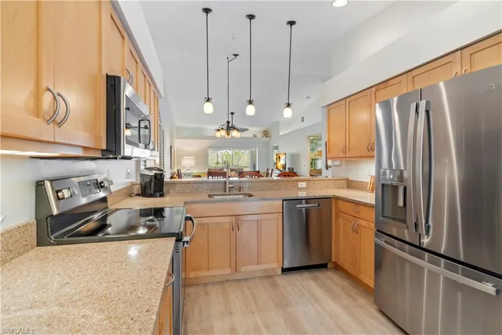 Kitchen featuring light brown cabinets, sink, hanging light fixtures, kitchen peninsula, and stainless steel appliances