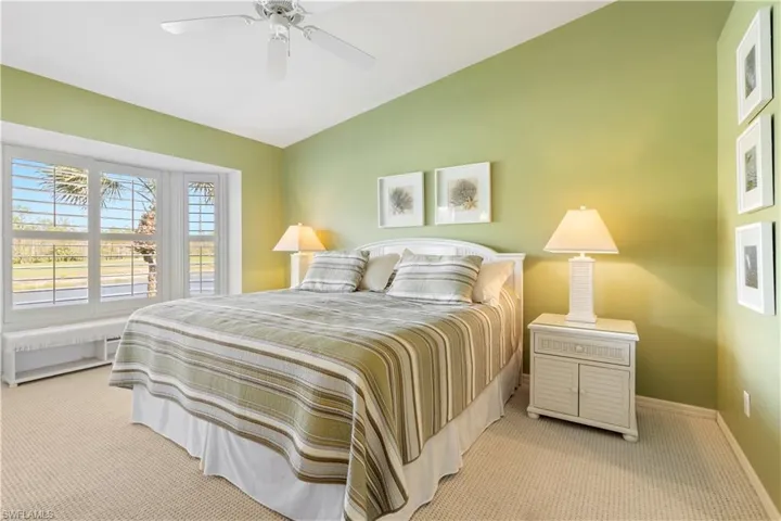 Bedroom featuring ceiling fan, light colored carpet, and lofted ceiling