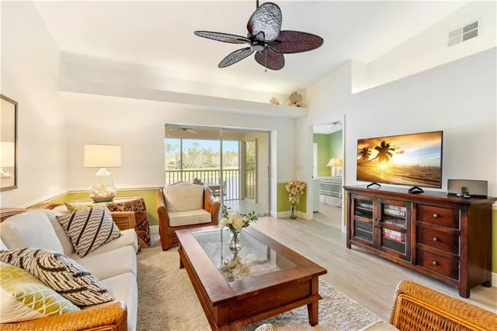 Living room with ceiling fan, light hardwood / wood-style floors, and lofted ceiling