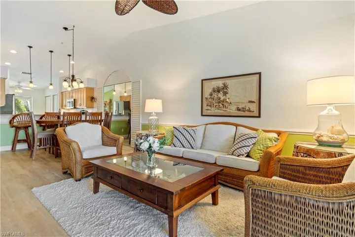 Living room with light hardwood / wood-style floors, vaulted ceiling, and ceiling fan
