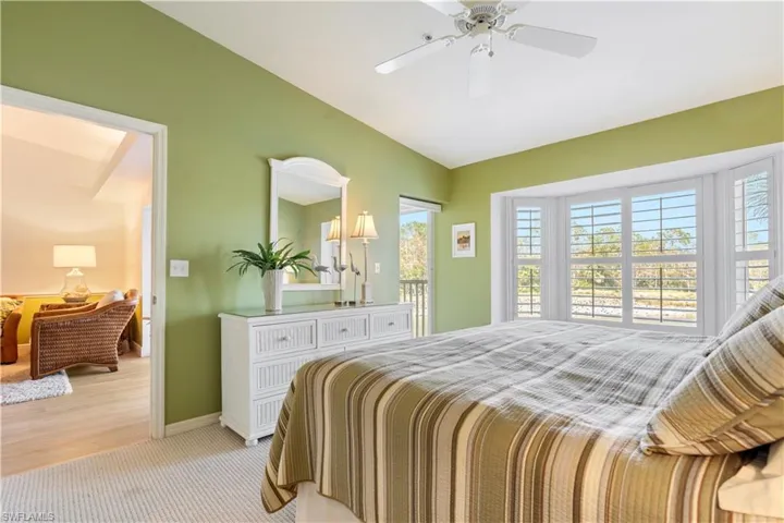 Carpeted bedroom featuring vaulted ceiling and ceiling fan