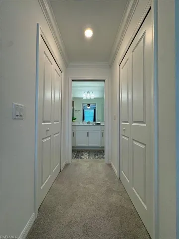 Corridor featuring ornamental molding and light colored carpet