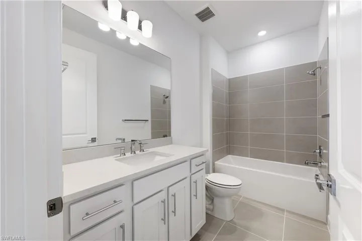 Bathroom featuring a single vanity with stone countertop, white cabinetry, and brushed nickel hardware