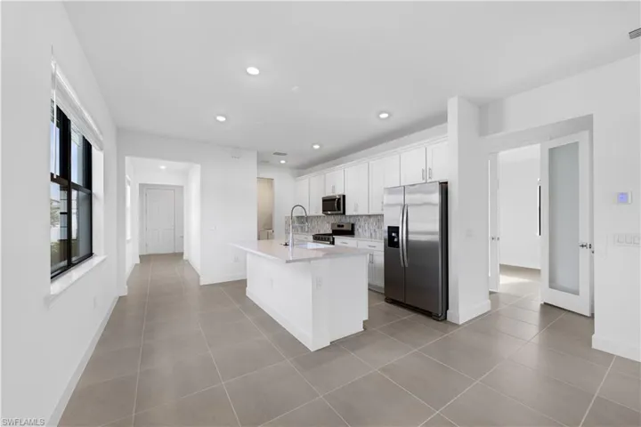 Modern kitchen featuring white cabinetry, stainless steel appliances, a center island with sink, and recessed lighting