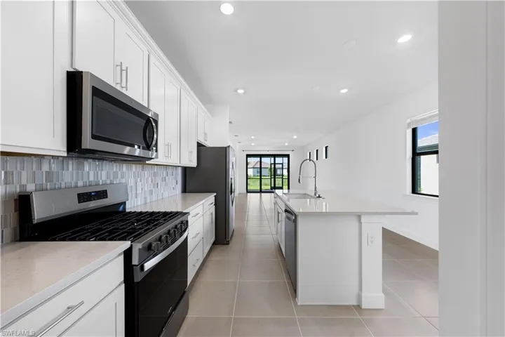 Contemporary kitchen featuring white cabinetry, light-toned countertops, and a mosaic tile backsplash