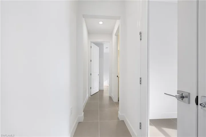 Clean architectural hallway with recessed lighting and neutral tile flooring