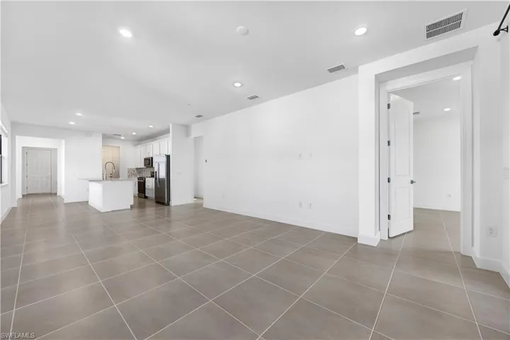 Open-concept living area with large format tile flooring and recessed lighting