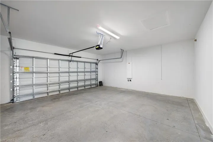 Spacious garage featuring a concrete floor, white painted walls, and an automatic overhead door opener
