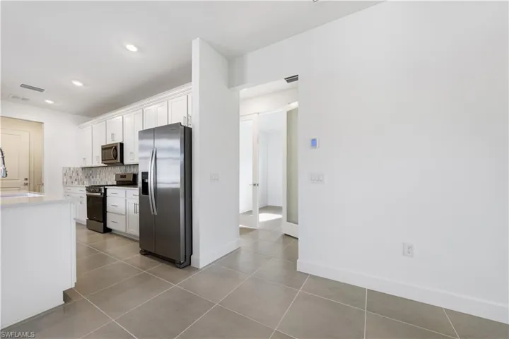 Kitchen featuring white shaker cabinetry, stainless steel appliances, and a tiled backsplash