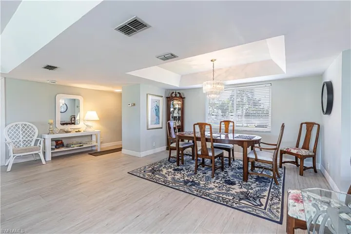 Dining area with a tray ceiling, a chandelier, and light wood-style flooring