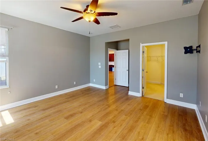 Unfurnished bedroom with ceiling fan, a closet, light wood-type flooring, and a spacious closet