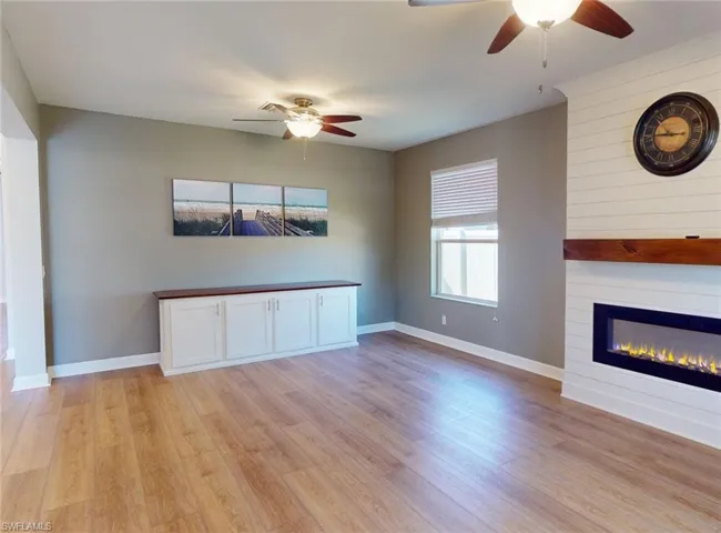 Unfurnished living room featuring ceiling fan, light hardwood / wood-style floors, and a fireplace