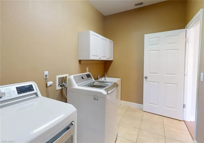 Laundry area featuring hookup for a washing machine, washer and dryer, cabinets, and light tile floors