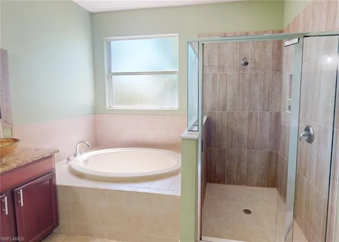 Bathroom with tile flooring, shower with separate bathtub, and vanity