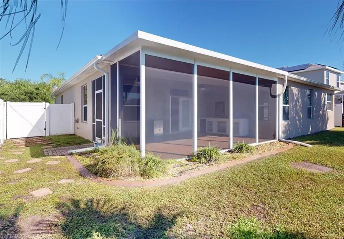 Rear view of property with a sunroom and a lawn