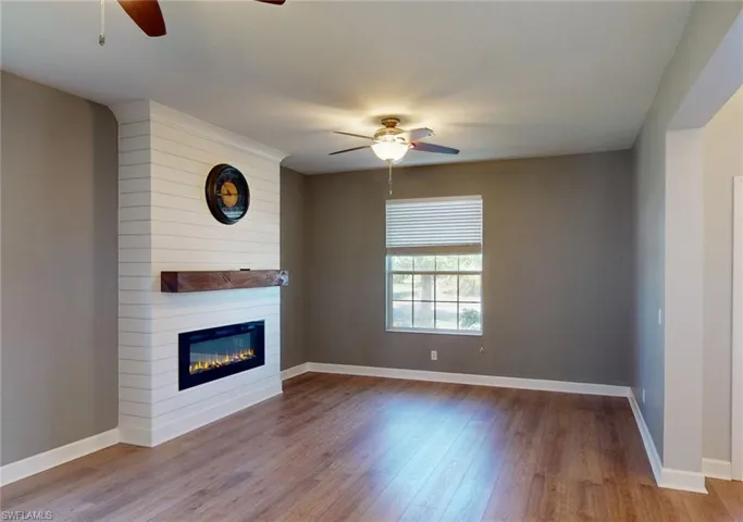 Unfurnished living room featuring a large fireplace, ceiling fan, and hardwood / wood-style floors