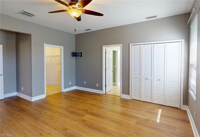 Unfurnished bedroom featuring a spacious closet, ceiling fan, and light wood-type flooring