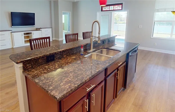 Kitchen with an island with sink, light hardwood / wood-style floors, and stainless steel dishwasher