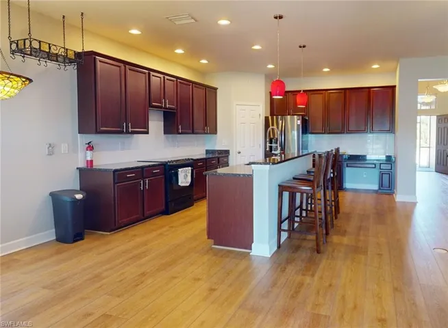 Kitchen featuring stainless steel refrigerator with ice dispenser, an island with sink, light hardwood / wood-style flooring, and electric range oven
