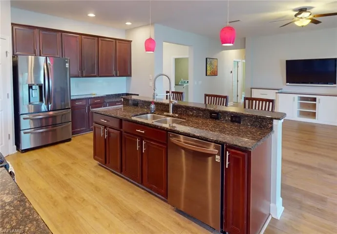 Kitchen with decorative light fixtures, washer / dryer, light hardwood / wood-style flooring, stainless steel appliances, and ceiling fan