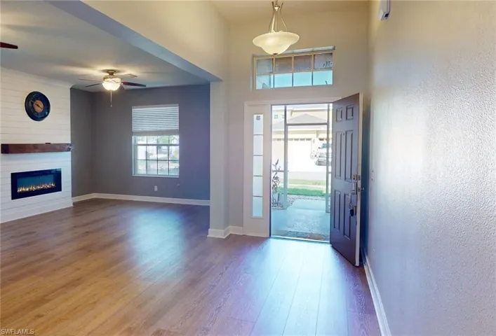 Entryway with a towering ceiling, a large fireplace, ceiling fan, and hardwood / wood-style floors