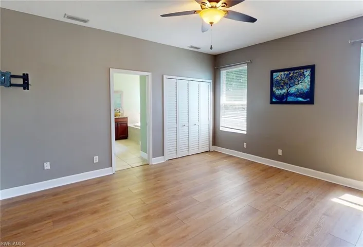 Unfurnished bedroom featuring light hardwood / wood-style floors, a closet, connected bathroom, and ceiling fan