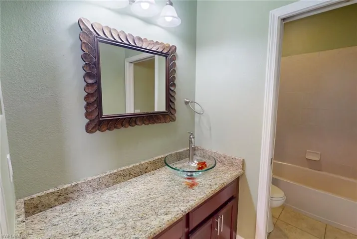 Full bathroom with shower / bathtub combination, tile flooring, vanity, and toilet