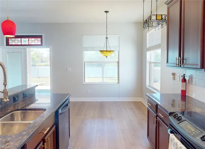 Kitchen with black electric range oven, plenty of natural light, tasteful backsplash, and stainless steel dishwasher