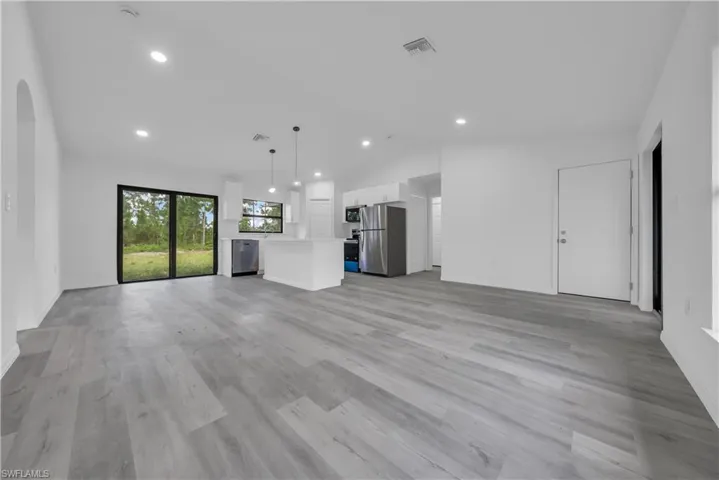 Unfurnished living room featuring light wood finished floors, recessed lighting, and vaulted ceiling