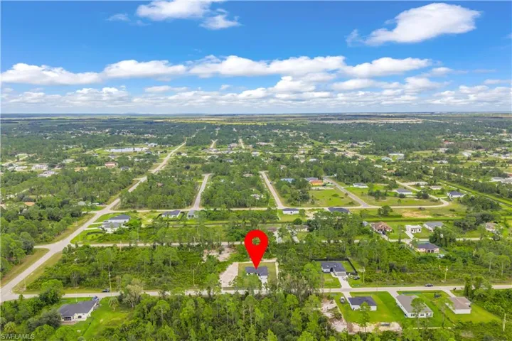 Aerial view of property's location featuring a tree filled landscape and nearby suburban area