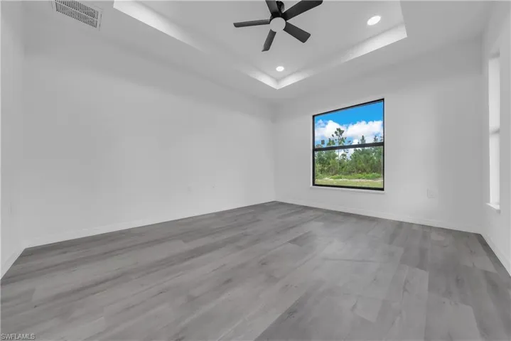 Unfurnished room with a tray ceiling, light wood-style flooring, recessed lighting, and a ceiling fan