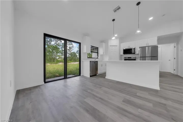 Kitchen featuring white cabinetry, appliances with stainless steel finishes, light countertops, hanging light fixtures, and a center island