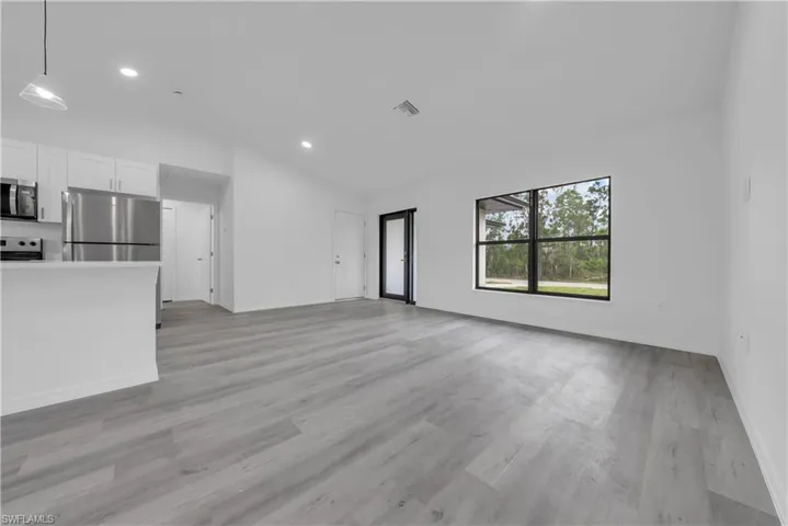 Unfurnished living room with lofted ceiling, light wood-style flooring, and recessed lighting