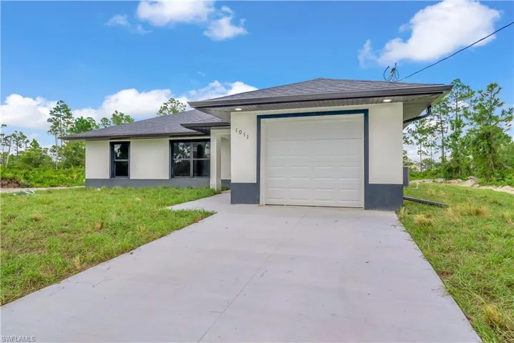 View of front of property featuring stucco siding, a front lawn, concrete driveway, and a shingled roof