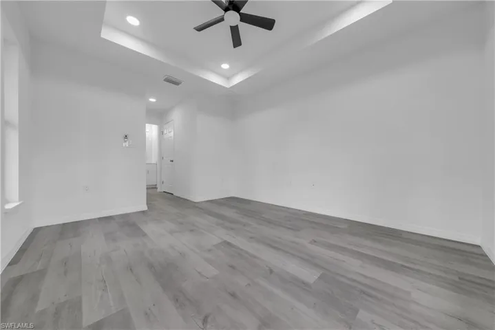 Spare room with a raised ceiling, light wood finished floors, recessed lighting, and ceiling fan