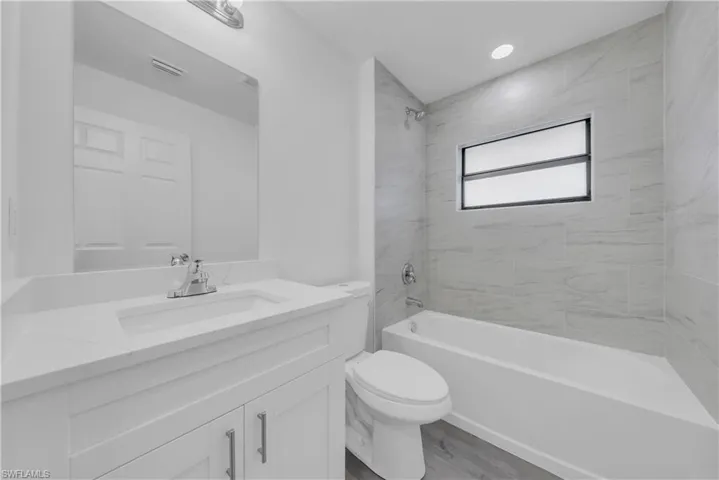 Full bathroom featuring tub / shower combination, vanity, and light wood-style flooring