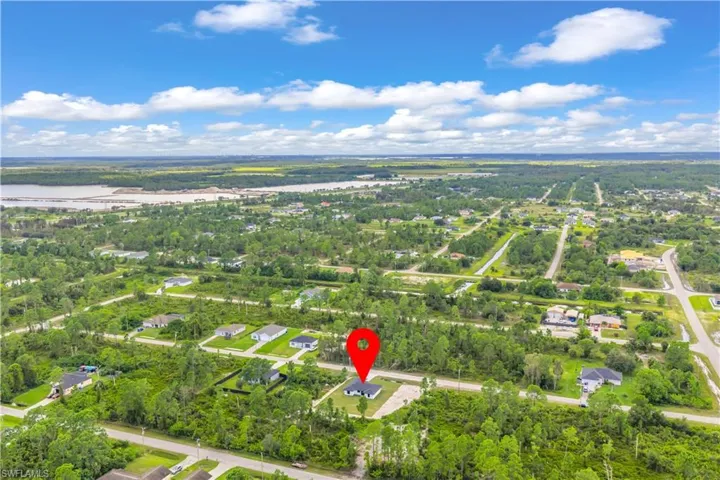 Aerial view of property and surrounding area featuring nearby suburban area and a large body of water
