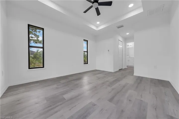 Spare room featuring a tray ceiling, recessed lighting, ceiling fan, and light wood finished floors