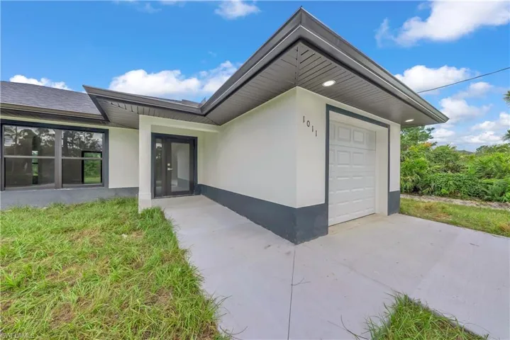 View of exterior entry with an attached garage, stucco siding, and concrete driveway