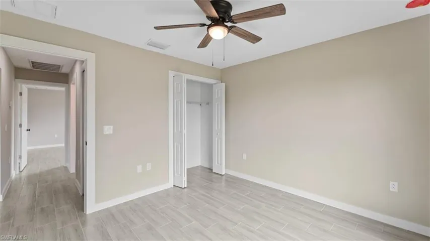 Unfurnished bedroom featuring a closet, visible vents, ceiling fan, and baseboards