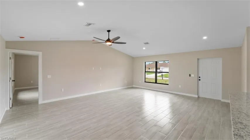 Unfurnished room with vaulted ceiling, ceiling fan, light wood-style flooring, and visible vents
