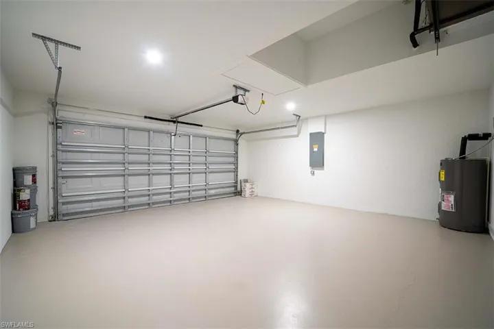 Garage with a garage door opener, electric panel, and water heater