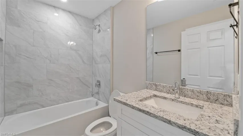 Bathroom with shower / washtub combination, vanity, and toilet