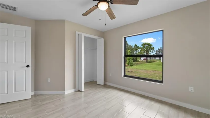 Unfurnished bedroom featuring a closet, visible vents, wood tiled floor, ceiling fan, and baseboards