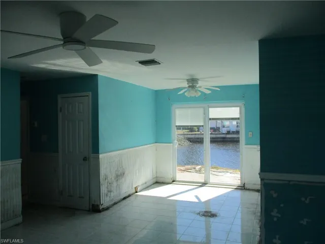 Unfurnished room with a wainscoted wall, a water view, and a ceiling fan