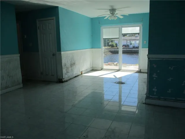 Tiled spare room with wainscoting, a water view, and ceiling fan